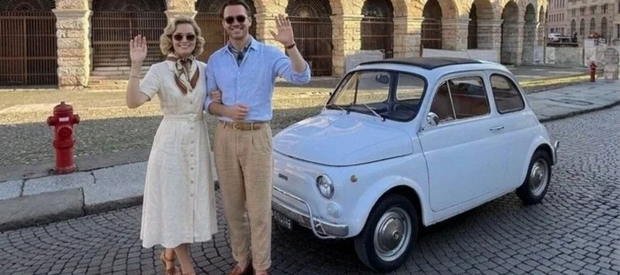 Fiat 500 azzurra ferma sul selciato davanti agli archi dell'Arena di Verona
